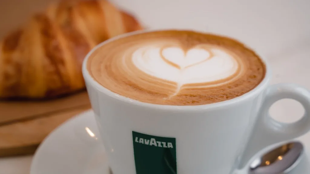 Lavazza Coffee On The Foreground And Croissant In The Background.